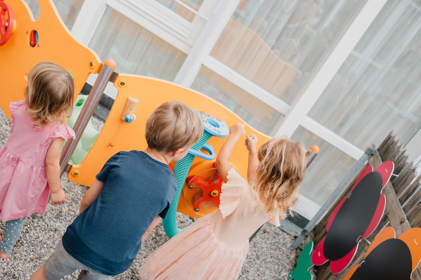 Kinder spielen gemeinsam an der Spielwand im Garten